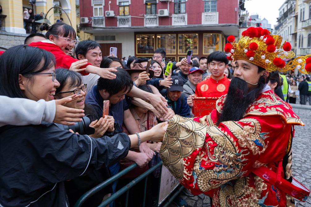 Homem vestido como o Deus da Fortuna interage com visitantes durante uma celebração da Festa da Primavera em Macau, sul da China, em 17 de fevereiro de 2026. (Xinhua/Cheong Kam Ka)
