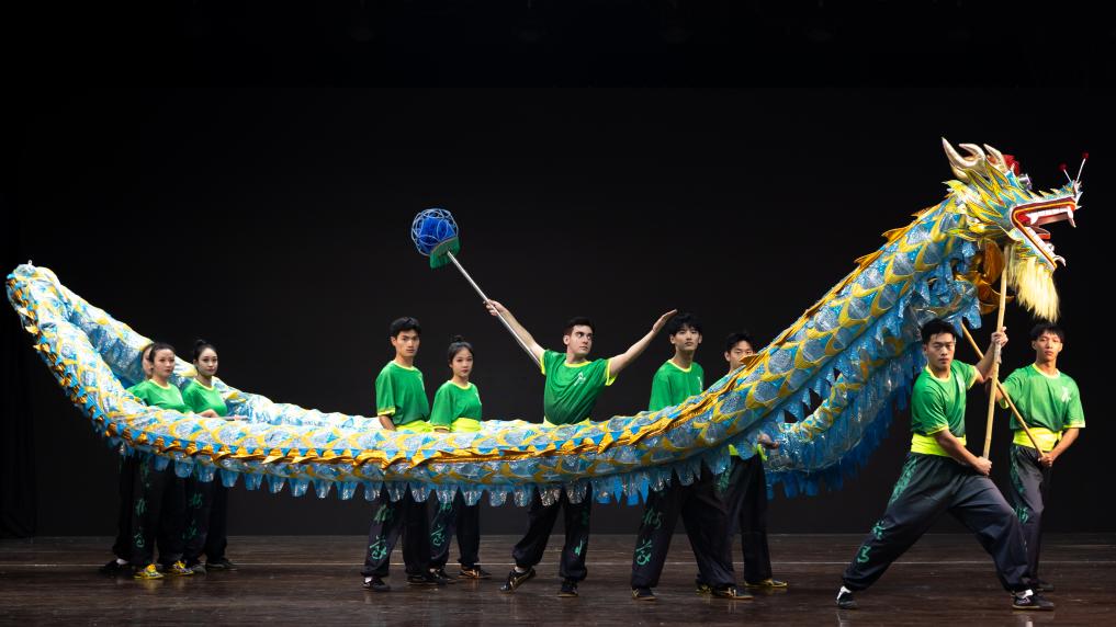 O estudante brasileiro Miguel de Oliveira Manacero (no centro) e seus companheiros estão apresentando a dança do dragão chinês. (Foto fornecida pelo entrevistado)